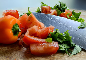 Fresh chopped tomatoes, peppers, and greens on a wooden cutting board