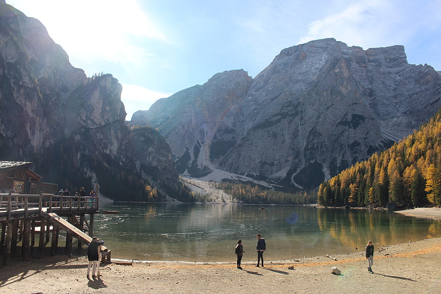 Autumn landscape of Pragser Wildsee lake with mountains and tourists
