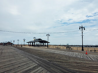 Empty wooden boardwalk with gazebo and pier under cloudy sky