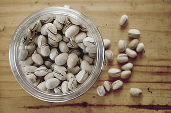 Top view of pistachios in glass jar on wooden table