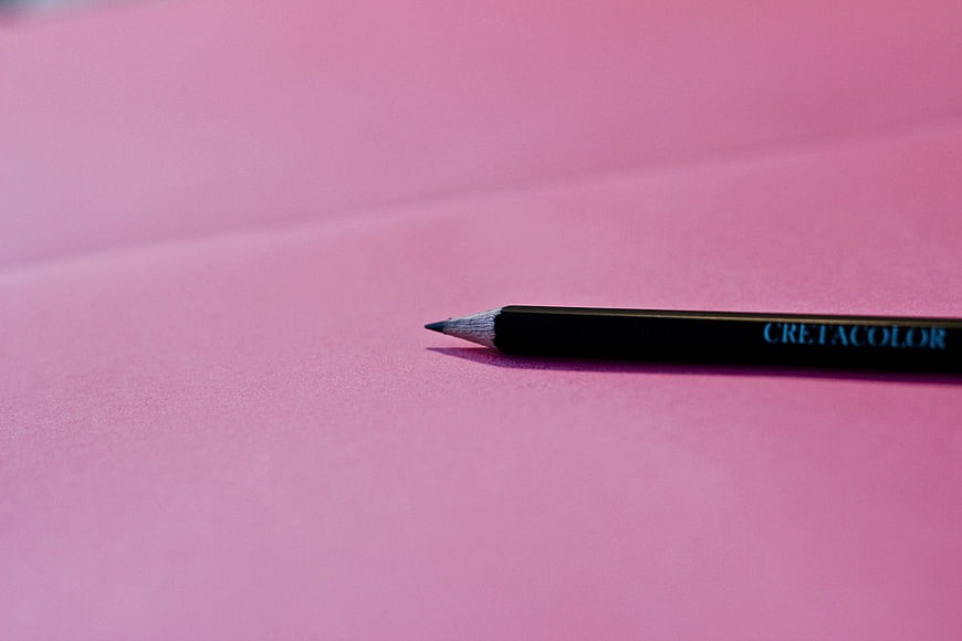 Black pencil on pink paper background