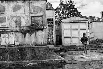 Lonely child standing in old black and white cemetery