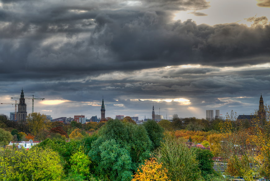 Dramatic cloudy sky over Groningen cityscape with autumn trees