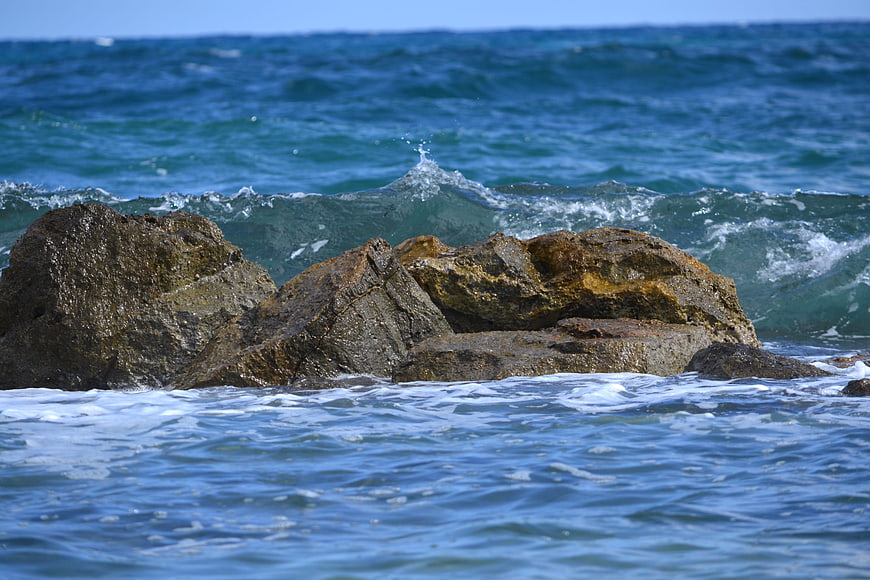 Rugged rocks in crashing ocean waves on a sunny day