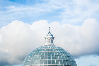 Glass dome architecture against blue sky with clouds