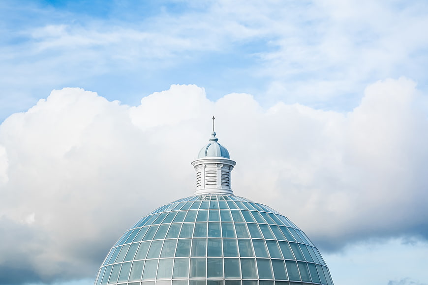 Glass dome architecture against blue sky with clouds