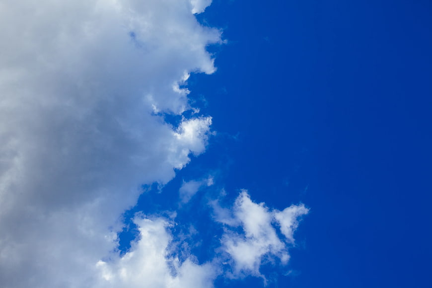 White clouds against a deep blue sky background