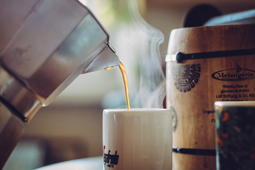 Hot Coffee Pouring from Moka Pot into White Mug