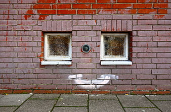 Pink brick wall with small windows and urban graffiti
