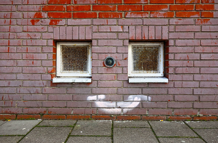 Pink brick wall with small windows and urban graffiti