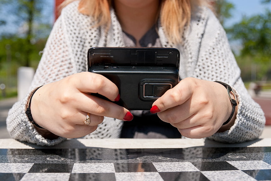 Woman Holding Vintage Slide Phone on Outdoor Table