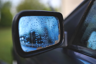 Raindrops on car side mirror with blurred background