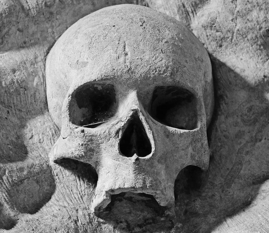 Close-up of weathered stone skull relief on church wall