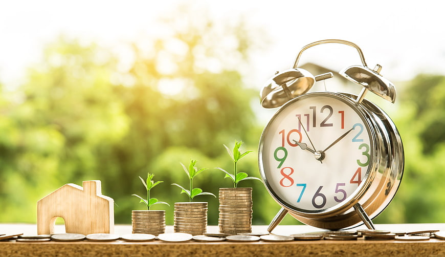 Financial Growth Concept with Coins, House, and Alarm Clock