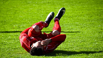 Injured soccer player clutching knee on green grass field