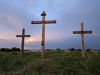 Three wooden crosses on grassy hill at dusk