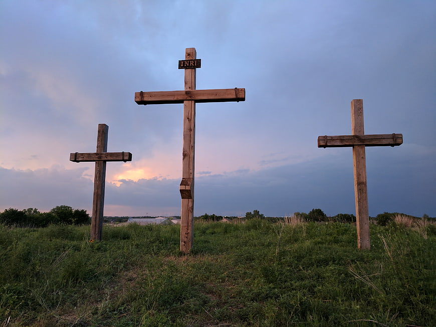 Three wooden crosses on grassy hill at dusk