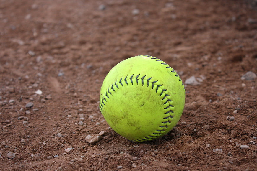 Close-up of a yellow softball on a dirt field