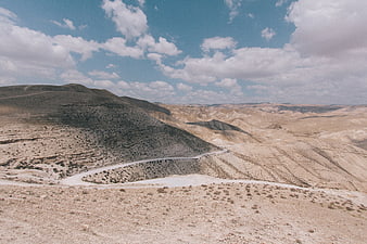 Winding Road Through Arid Desert Hills Under Blue Sky