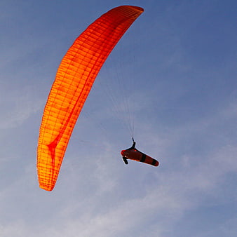 Orange Paramotor Flying Against Blue Sky
