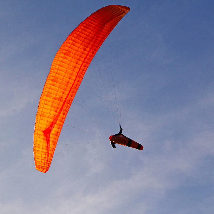 Orange Paramotor Flying Against Blue Sky