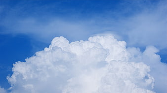 Fluffy white cumulus clouds against a bright blue sky