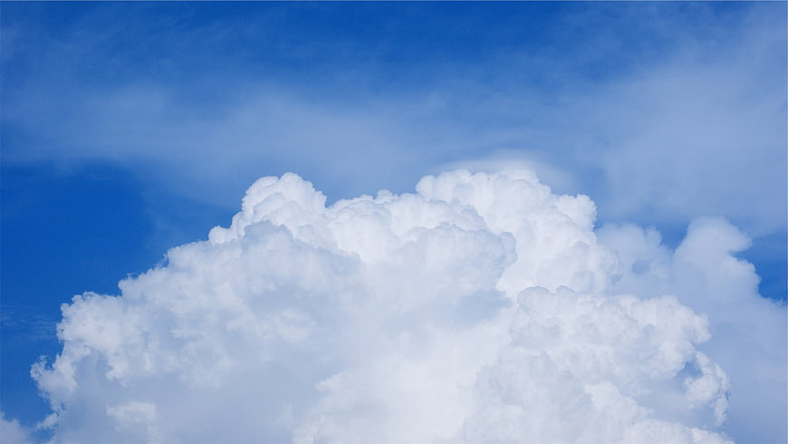 Fluffy white cumulus clouds against a bright blue sky