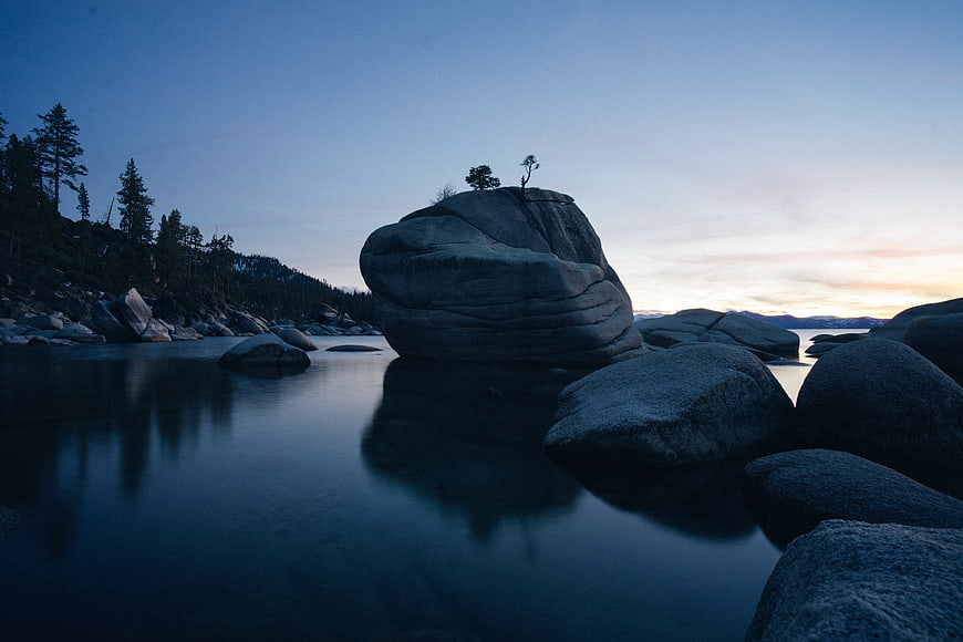 Serene Blue Hour Landscape with Large Rock Formation in Calm Water