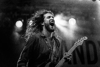Passionate male rock musician singing and playing guitar on stage