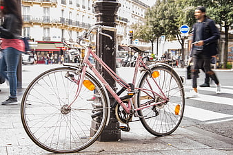 Pink bicycle locked to post on busy Paris street