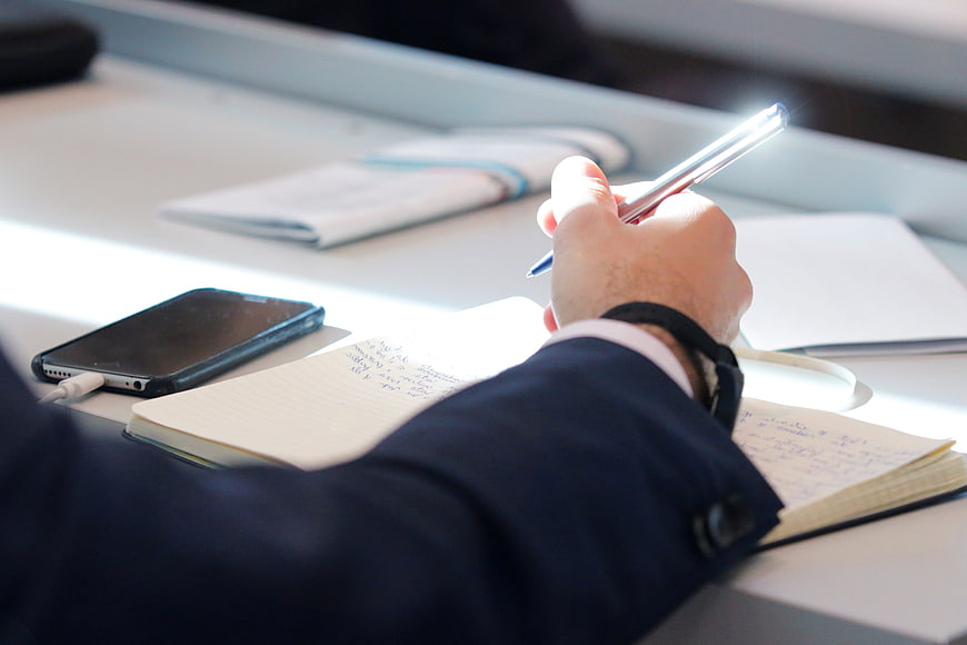 Businessman Writing Notes In Notebook During Conference Meeting
