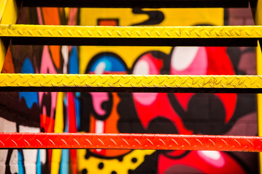Colorful Graffiti Art Behind Yellow and Red Metal Stairs