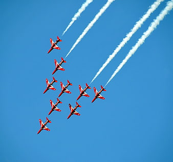 Red and white jets flying in formation with smoke trails