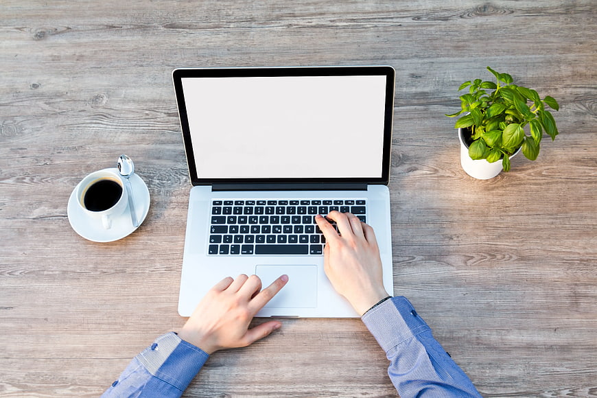 Top View of Hands Typing on Laptop with Coffee and Plant