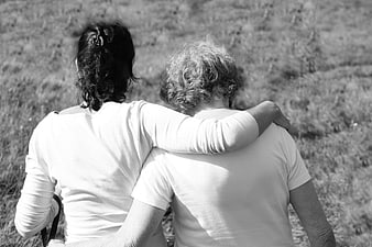 Black and white photo of two women embracing in a field