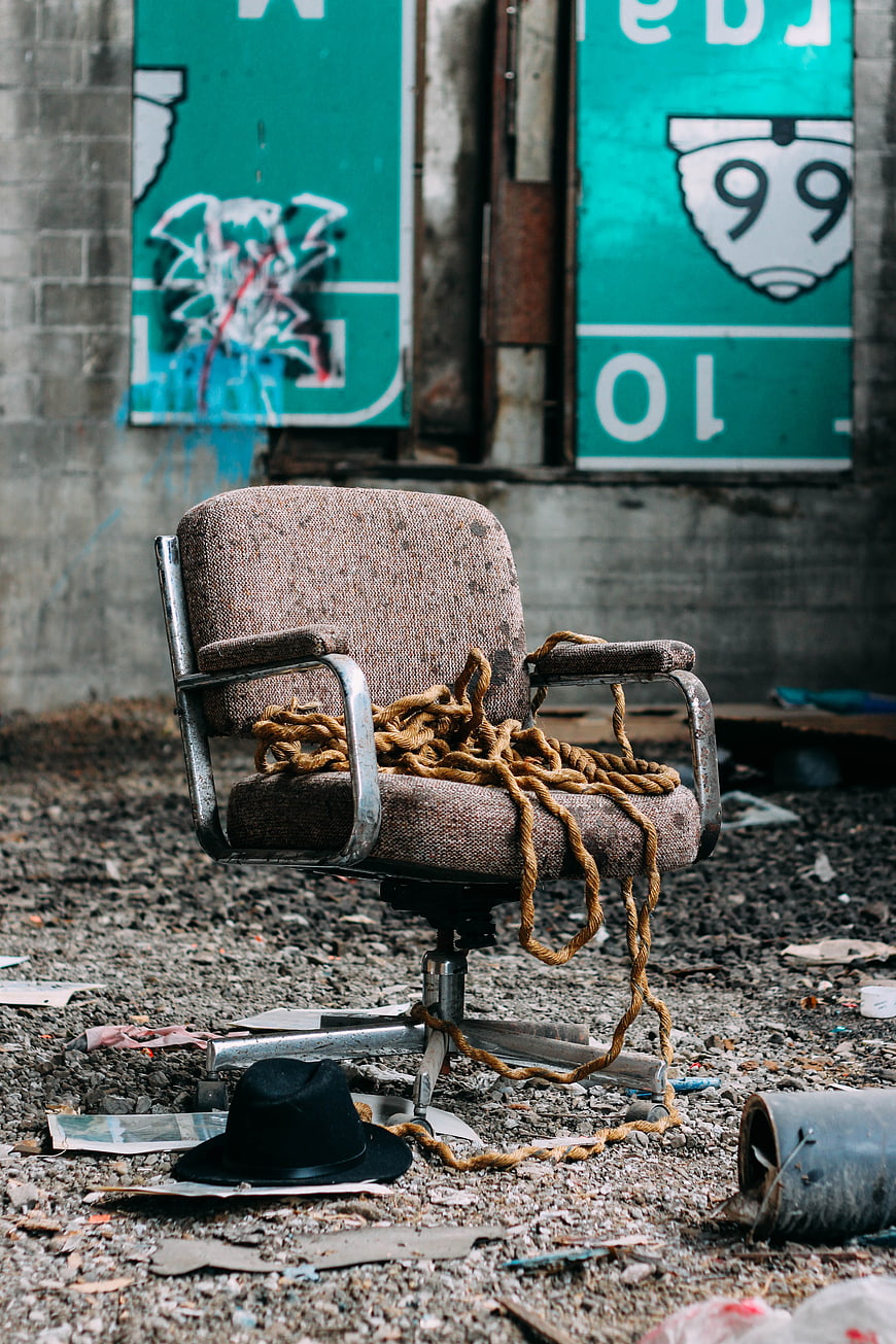 Old office chair with rope and hat in abandoned warehouse