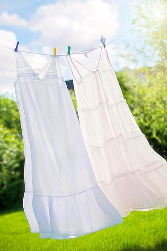White Summer Dresses Drying on Clothesline in Sunny Garden