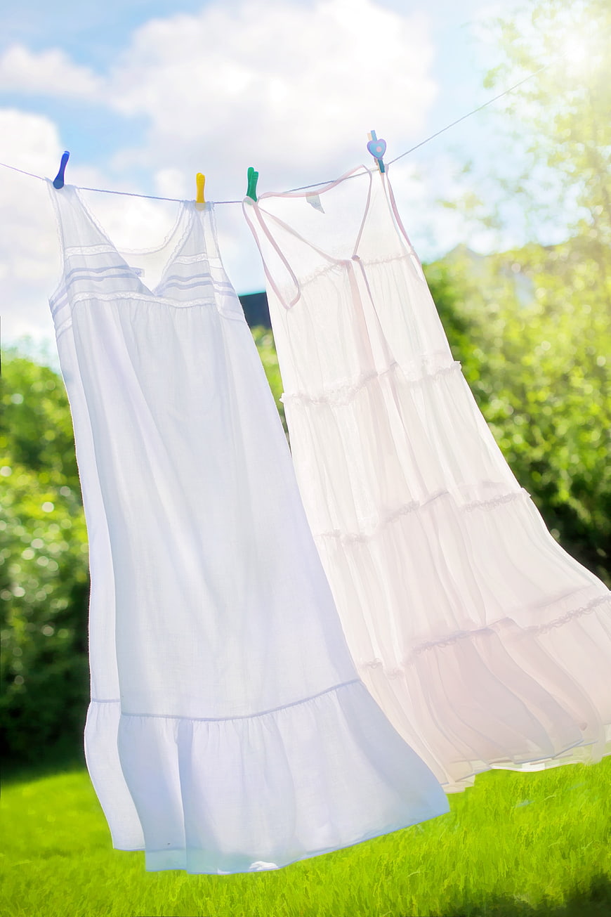 White Summer Dresses Drying on Clothesline in Sunny Garden