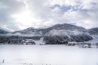 Snowy mountain landscape with mist and frozen lake