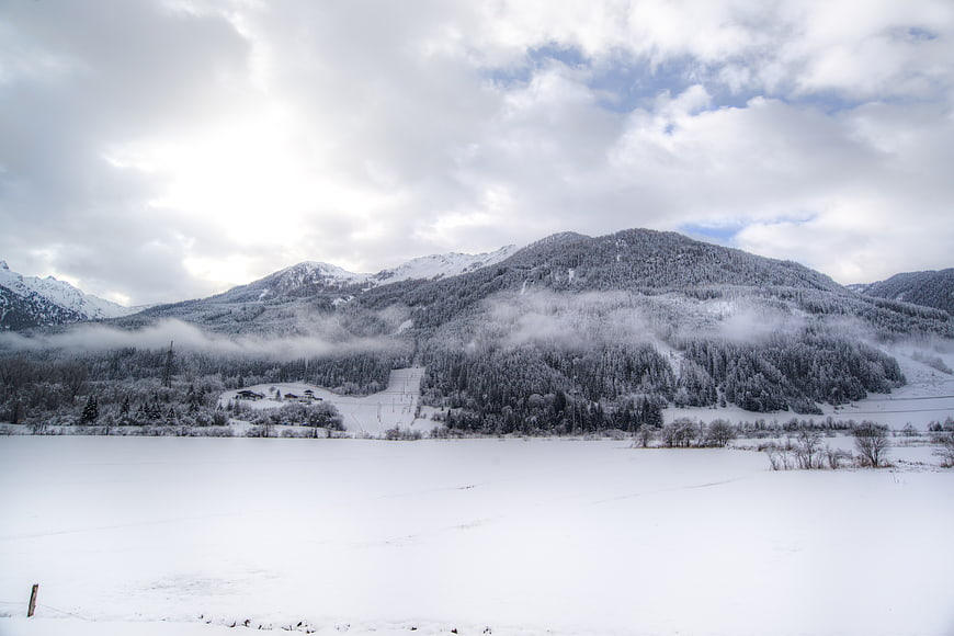 Snowy mountain landscape with mist and frozen lake