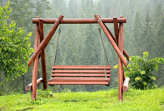 Empty wooden swing bench in green forest clearing