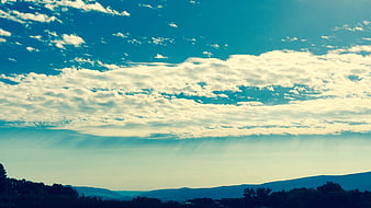 Dramatic blue sky with textured clouds over distant mountains