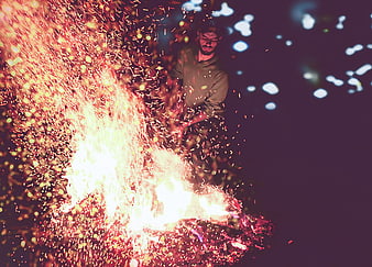 Man Tending Bonfire with Sparks Flying at Night