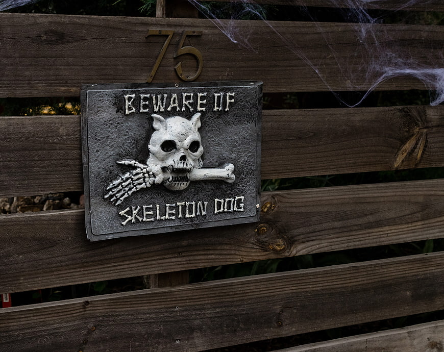 Beware of Skeleton Dog Halloween Sign on Wooden Fence