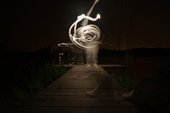 Light painting abstract swirl on wooden pier at night