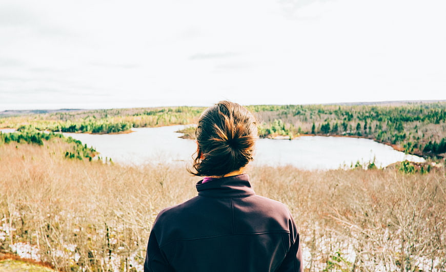 Woman Looking Out Over Lake and Forest Landscape