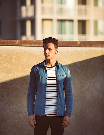 Young man in denim shirt standing on urban rooftop