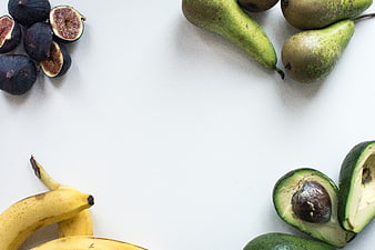 Top view of fresh figs, bananas, pears, and avocados on white