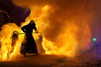 Silhouette of fire performer with flaming staff at night