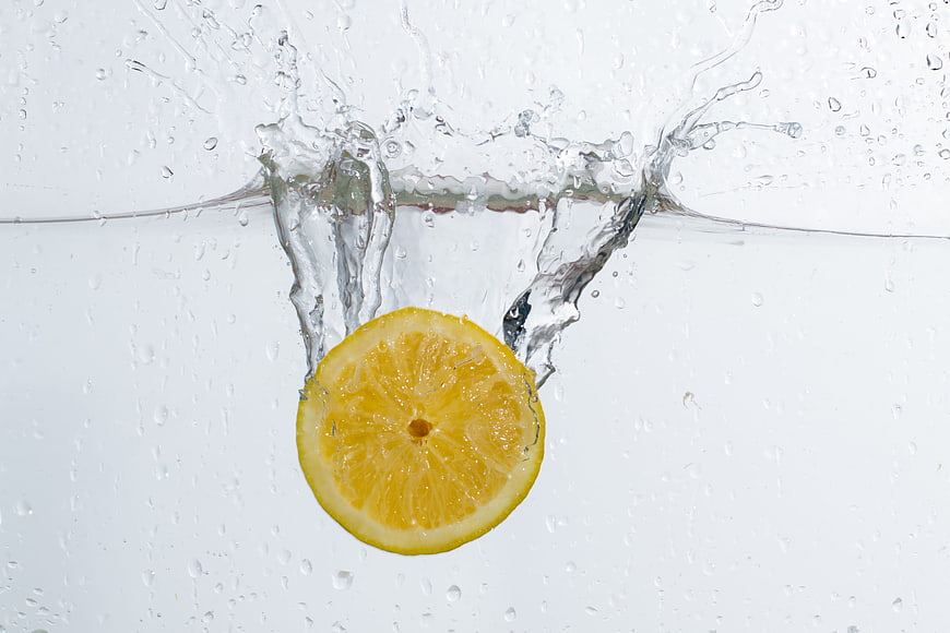 Fresh Lemon Slice Splashing into Clear Water